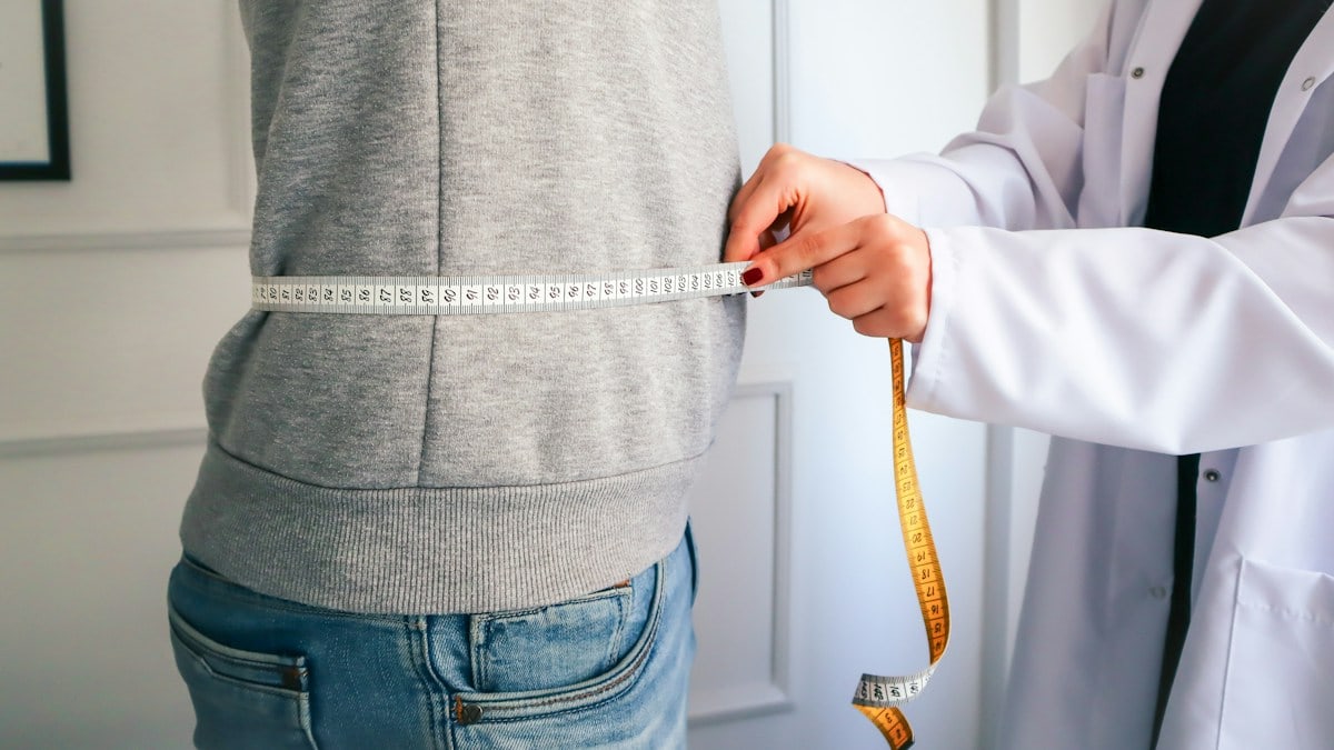 a woman measuring her waist with a measuring tape